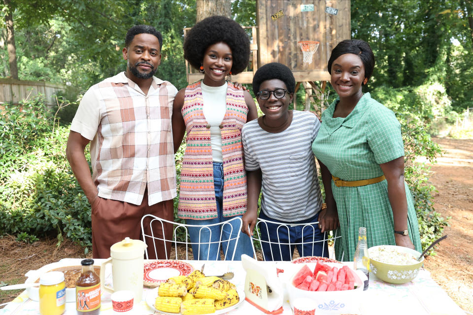 The cast of "The Wonder Years" stand together behind an outdoor table set with food