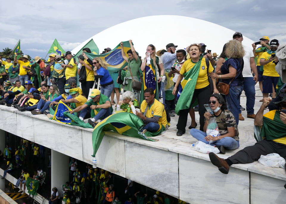 Protesters, supporters of Brazil's former President Jair Bolsonaro, stand on the roof of the National Congress building after they stormed it, in Brasilia, Brazil, Sunday, Jan. 8, 2023. (AP Photo/Eraldo Peres)