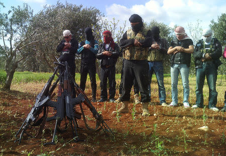 FILE PHOTO: Members of the Free Syrian Army pray near their weapons in the outskirts of Taftanaz village, east of Idlib city, Syria April 12, 2012. REUTERS/Stringer/File Photo