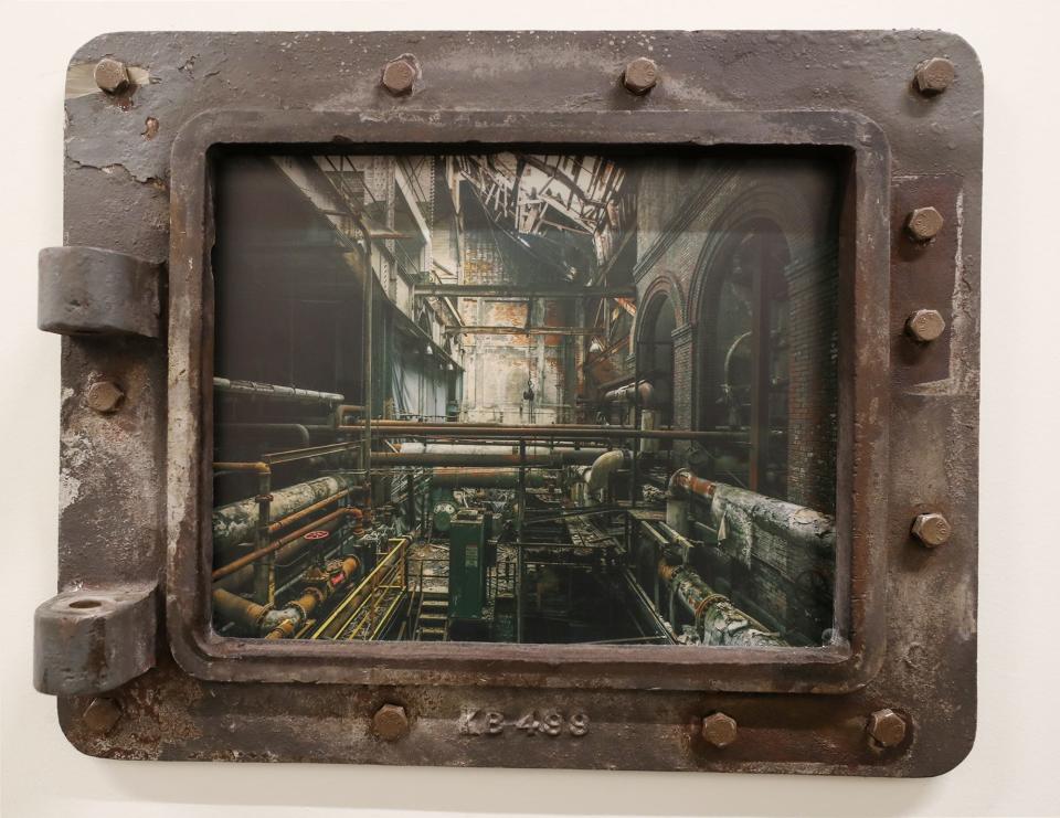 A coal hatch flange that was repurposed as a picture frame with a photo printed on metal of the interior of the old B.F. Goodrich power plant at Bounce Innovation Hub in Akron.