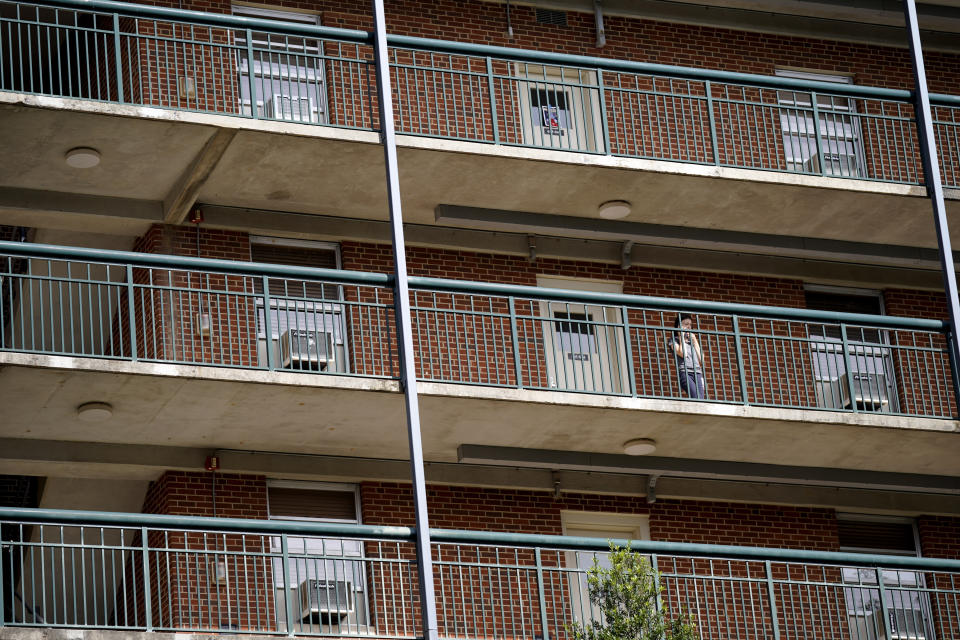 A students stands on the balcony of Ehringhaus dormitory on campus at the University of North Carolina in Chapel Hill, N.C., Tuesday, Aug. 18, 2020. The university announced that it would cancel all in-person undergraduate learning starting on Wednesday following a cluster of COVID-19 cases which caused some students to pack and leave campus. (AP Photo/Gerry Broome)