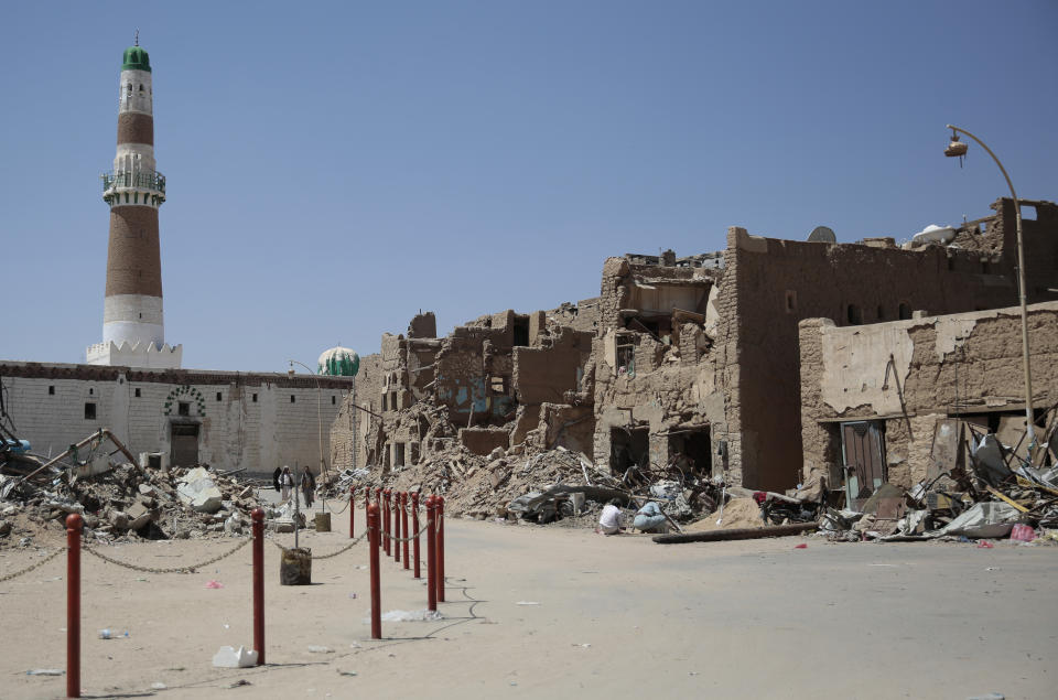 FILE - In this Oct. 9, 2016 file photo, Yemeni men walk past damaged houses by Saudi-led airstrikes, in the Old City of Saada, Yemen. A prominent Yemeni rights group has documented heavy damage to at least 34 archaeological sites from the fighting and airstrikes over the past four years. In a report released Thursday, Nov. 15, 2018, the Mawatana Organization for Human Rights said that it collected testimonies from over 75 people working at the archaeological sites and monuments that came under attack since mid-2014. (AP Photo/Hani Mohammed)