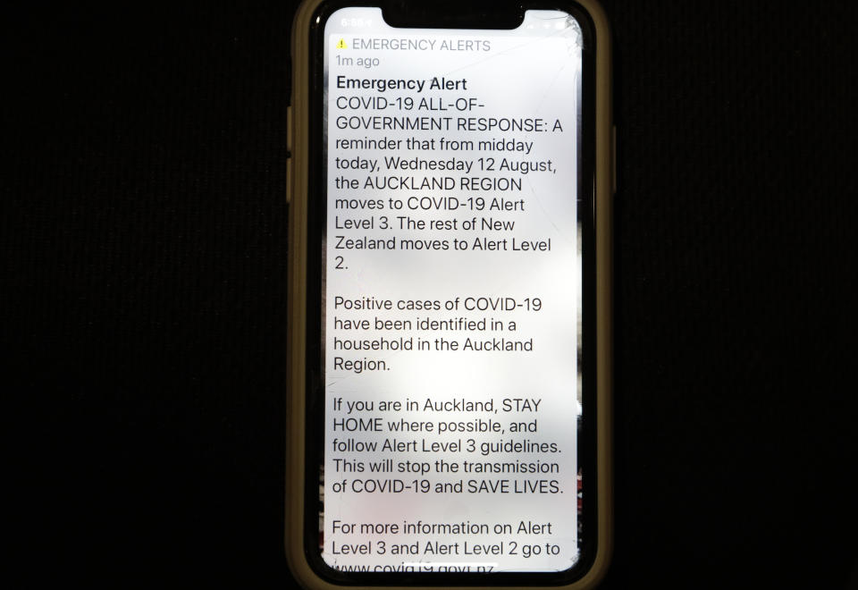 A news alert is displayed on a mobile phone in Christchurch, New Zealand, Wednesday, Aug. 12, 2020. New Zealand Prime Minister Jacinda Ardern said Tuesday, Aug. 11, 2020, that authorities have found four cases of the coronavirus in one Auckland household from an unknown source, the first cases of local transmission in the country in 102 days. (AP Photo/Mark Baker)