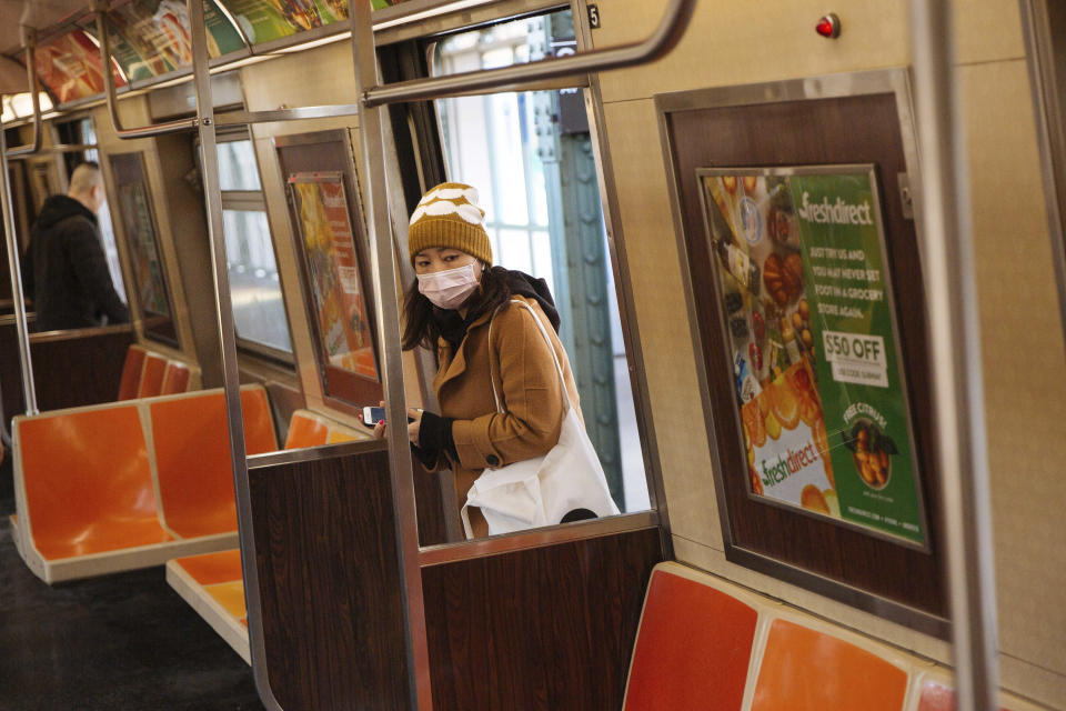 A passenger boards the N Train while wearing a face mask amid fears of the spread of the coronavirus, Wednesday, March 11, 2020, in New York. (AP Photo/Kevin Hagen)