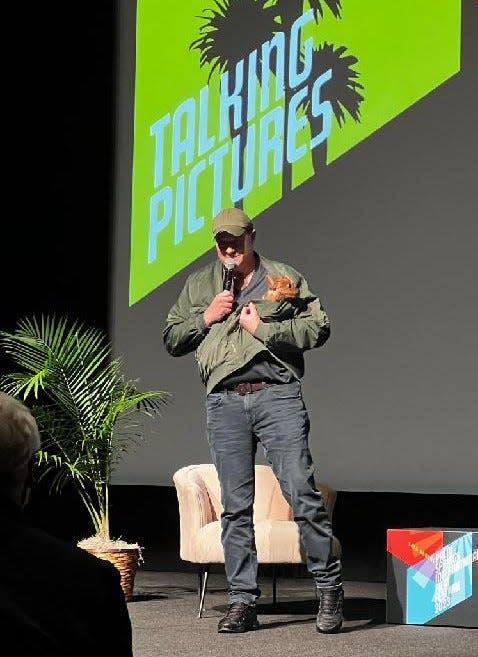Actor Brendan Fraser reveals his dog Pee Wee from under his coat at the start of a Q&A after screening his film "The Whale" at Palm Springs High School during the Palm Springs International Film Festival on Thursday.