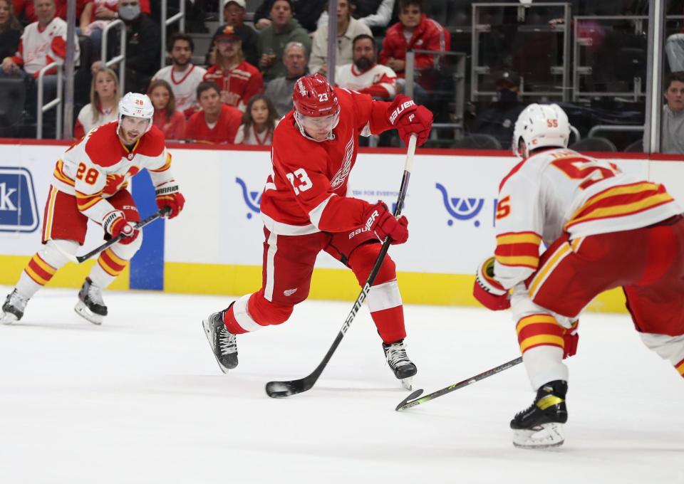 Detroit Red Wings right wing Lucas Raymond (23) shoots against Calgary Flames defenseman Noah Hanifin (55) during third period action Thursday, Oct. 21, 2021 at Little Caesars Arena.