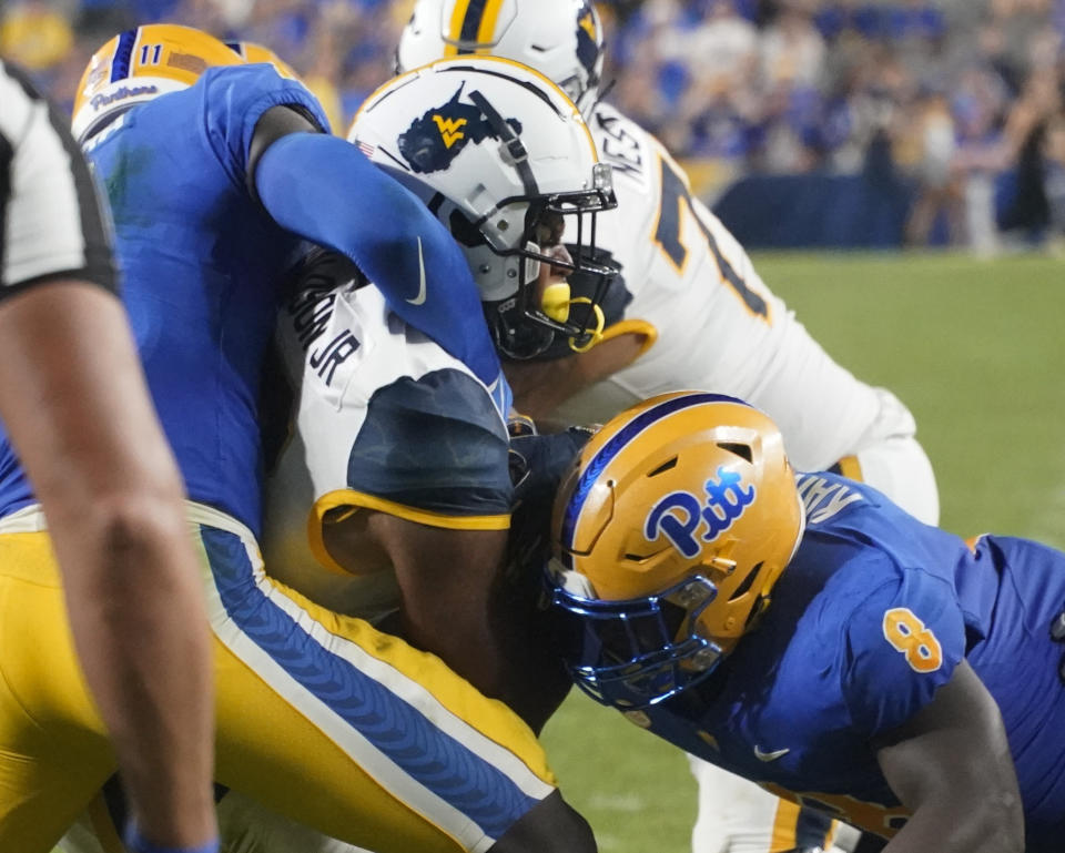 West Virginia tight end CJ Donaldson, center, scores a touchdown as Pittsburgh defensive lineman Calijah Kancey (8) and linebacker Bangally Kamara (11) hit him during the second half of an NCAA college football game, Thursday, Sept. 1, 2022, in Pittsburgh. (AP Photo/Keith Srakocic)