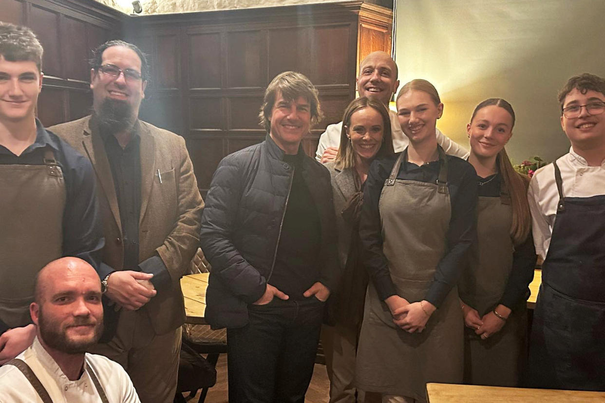 Tom Cruise stands beside staff at Restaurant Lovage in Bakewell, Derbyshire, after dining there on March 5 2024.  Release date March 7 2024. See SWNS story SWSMcruise. Hollywood A-lister Tom Cruise poses for pictures with starstruck restaurant staff after stopping for dinner while filming Mission Impossible in the Peak District. The grinning star, sporting long hair and an all-black ensemble, sent pulses racing when he dined at Restaurant Lovage, in the beautiful village of Bakewell, Derbys. Cruise, 61, was snapped sitting in a battered 4x4 vehicle on Tuesday (March 5) while filming the next instalment of his action movie franchise in a nearby abandoned mine.(Restaurant Lovage / SWNS)