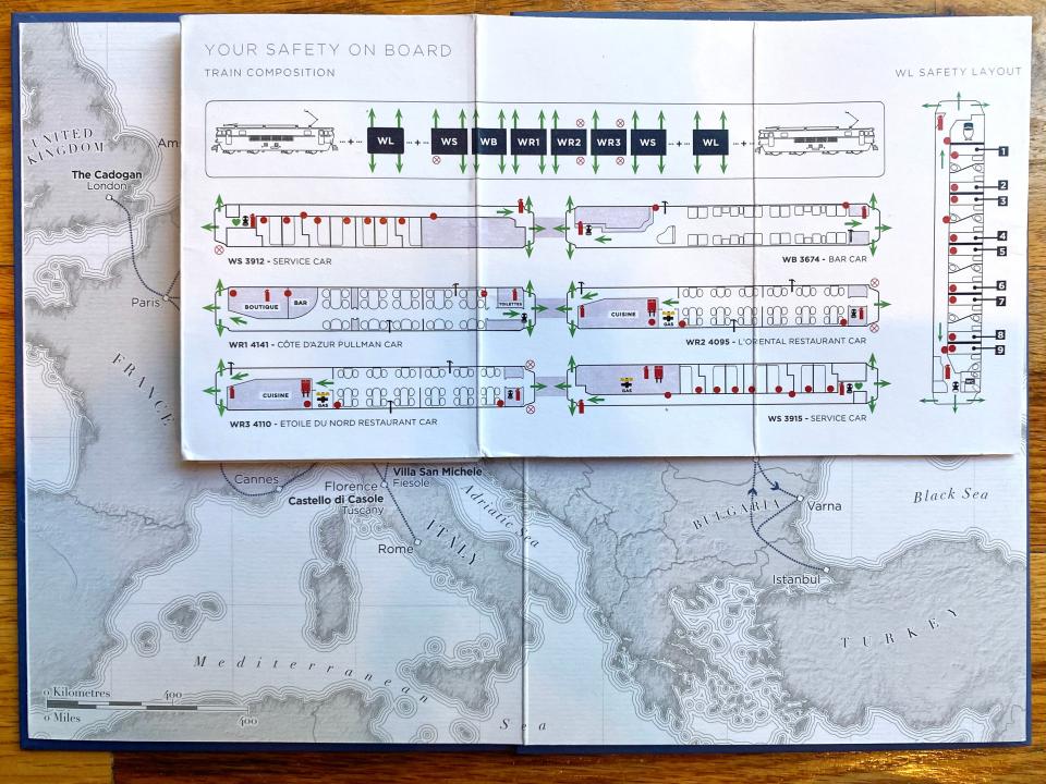 On a wood floor, a white map of Italy behind a white pamphlet showing the train's layout.