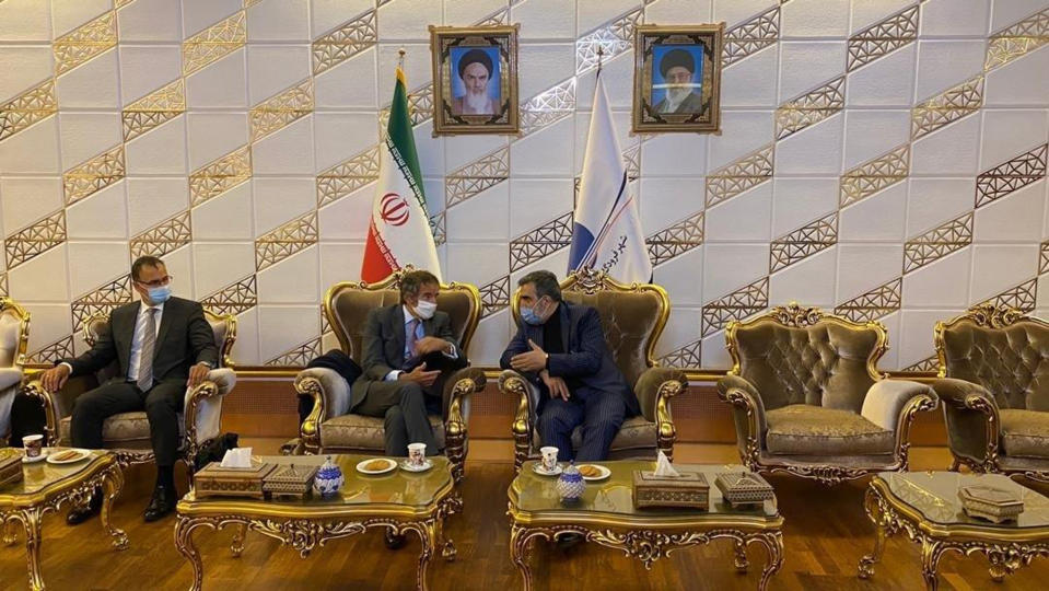 Director General of International Atomic Energy Agency, IAEA, Rafael Mariano Grossi, center, listens to spokesman of Iran's atomic agency Behrouz Kamalvandi upon his arrival at Tehran's Imam Khomeini airport, Iran, Monday, Aug. 24, 2020. The man at left is unidentified. Portraits of the late revolutionary founder Ayatollah Khomeini, left, and Supreme Leader Ayatollah Ali Khamenei hang on the wall. (Atomic Energy Organization of Iran via AP)