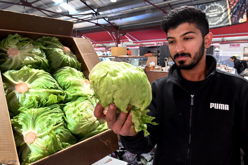 Syed Hyder sostiene una lechuga en un puesto de hortalizas en el Mercado Reina Victoria de Melbourne, el 7 de junio de 2022. El precio local del vegetal ha subido hasta 300 por ciento en los últimos meses. (Foto AFP).