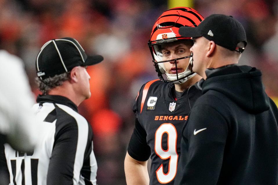 Cincinnati Bengals quarterback Joe Burrow and head coach Zac Taylor speak with an official as the decision to suspend play is made Monday.