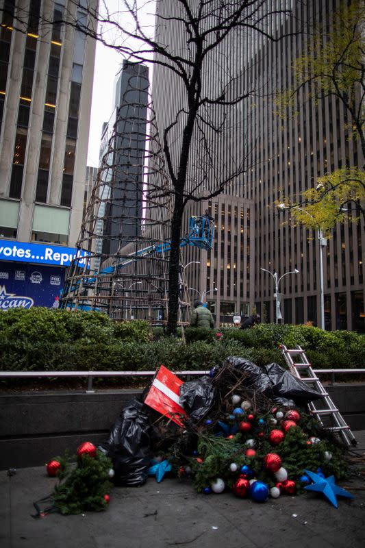Workers clean up the burnt remains of a Christmas tree outside the News Corp. and Fox News building in New York