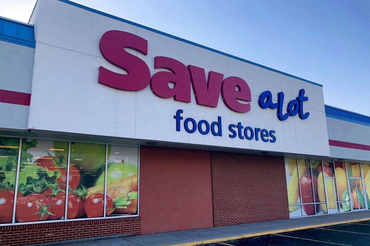 Save A Lot store sign exterior front with windows showing fresh vegetables photo, few empty parking spaces