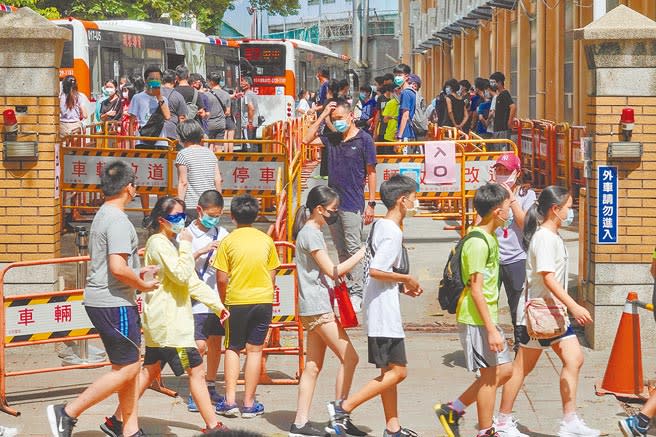 台北市松山區一所國中有學生確診，學生全部被召回學校篩檢，該校學生暫時在校外圍牆邊等候，再依班級順序入校採檢。（黃子明攝）