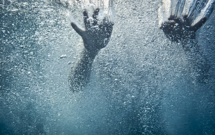 Underwater view of hands reaching through bubbles and water