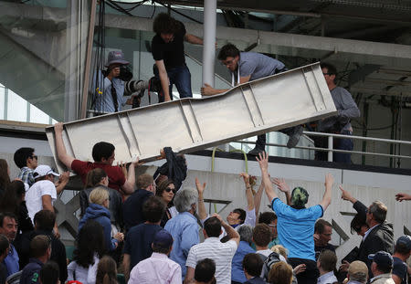 Spectators remove a metal structure which collapsed in the tribune on the Philippe Chartier tennis court during the men's quarter-final match between Jo-Wilfried Tsonga of France and Kei Nishikori of Japan during the French Open tennis tournament at the Roland Garros stadium in Paris, France, June 2, 2015. REUTERS/Pascal Rossignol