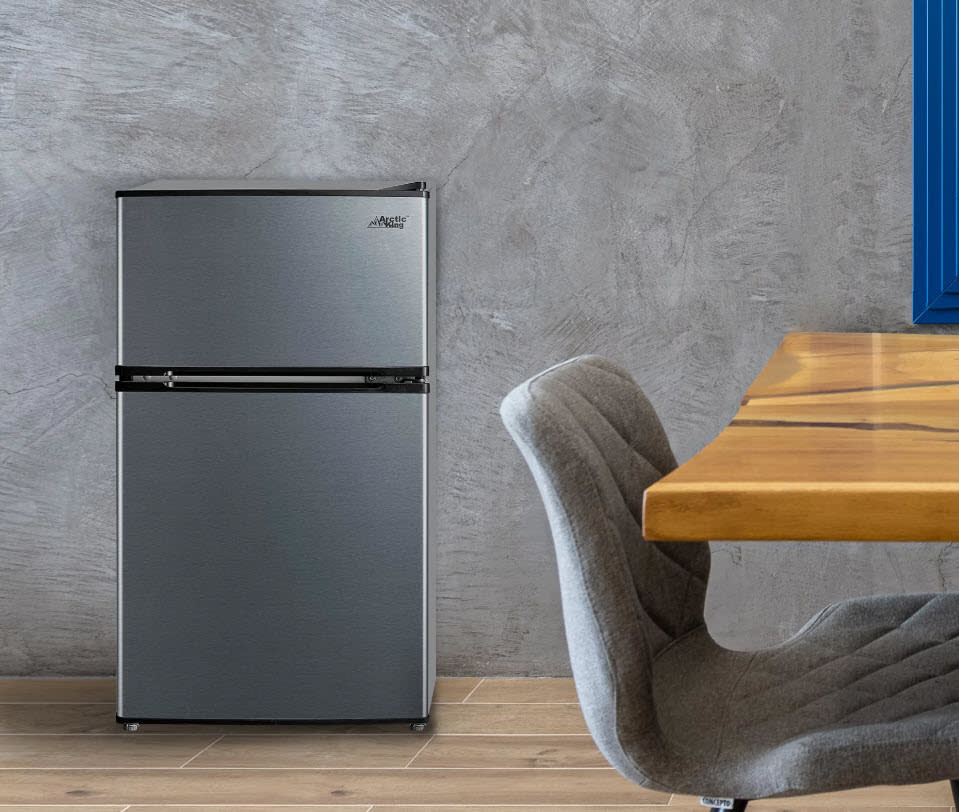 medium size sterling silver mini fridge next to a desk