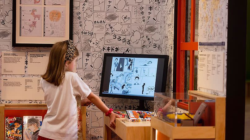 A young girl looks at an interactive display, from Japan: Myths to Manga at Young V&A. 