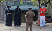 A Sri Lankan police officer detains curfew violators during a curfew imposed to curb the spreading of new coronavirus in Colombo, Sri Lanka, Wednesday, April 1, 2020. The new coronavirus causes mild or moderate symptoms for most people, but for some, especially older adults and people with existing health problems, it can cause more severe illness or death. (AP Photo/Eranga Jayawardena)