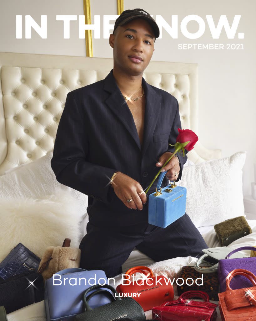 Brandon Blackwood on In The Know’s September digital cover. He’s wearing an <a href="https://fave.co/3sP9FfO" rel="noopener" target="_blank" data-ylk="slk:MM6 Maison Margiela jumpsuit;elm:context_link;itc:0;sec:content-canvas" class="link ">MM6 Maison Margiela jumpsuit</a>, <a href="https://fave.co/3DyPnw3" rel="noopener" target="_blank" data-ylk="slk:Alexander Wang booties;elm:context_link;itc:0;sec:content-canvas" class="link ">Alexander Wang booties</a> and a <a href="https://fave.co/2Y4N4Rn" rel="noopener" target="_blank" data-ylk="slk:New York Yankees baseball cap;elm:context_link;itc:0;sec:content-canvas" class="link ">New York Yankees baseball cap</a>. He’s holding a <a href="https://fave.co/2WAdV75" rel="noopener" target="_blank" data-ylk="slk:Brandon Blackwood Mini Kendrick Trunk;elm:context_link;itc:0;sec:content-canvas" class="link ">Brandon Blackwood Mini Kendrick Trunk</a> and is surrounded by an assortment of other Brandon Blackwood bags.<br>Photo by <a href="https://www.instagram.com/sheekswinsalways/?hl=en" rel="nofollow noopener" target="_blank" data-ylk="slk:Shaniqwa Jarvis;elm:context_link;itc:0;sec:content-canvas" class="link ">Shaniqwa Jarvis</a>