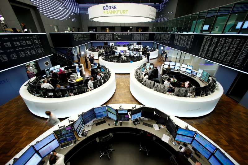 FILE PHOTO: Traders work at their desks in front of the German share price index, DAX board, at the stock exchange in Frankfurt, Germany February 28, 2017. REUTERS/Staff/Remote/File Photo