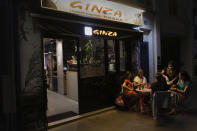 Shao Lin Tia serves diners at a table outside Ginza, the pan-Asian restaurant she runs with her husband on Rue Daguerre, a classic market street in Paris, on Thursday, July 9, 2020. Under French rules, grocery stores, butchers, wine shops and cheese shops were considered essential during the nationwide confinement to slow the spread of the coronavirus. Restaurants, even for takeout, were not. The rules have gradually relaxed, first for takeout only, then for a few outdoor tables, but sales remain low and Tia worries that the hardest is yet to come. (AP Photo/Francois Mori)