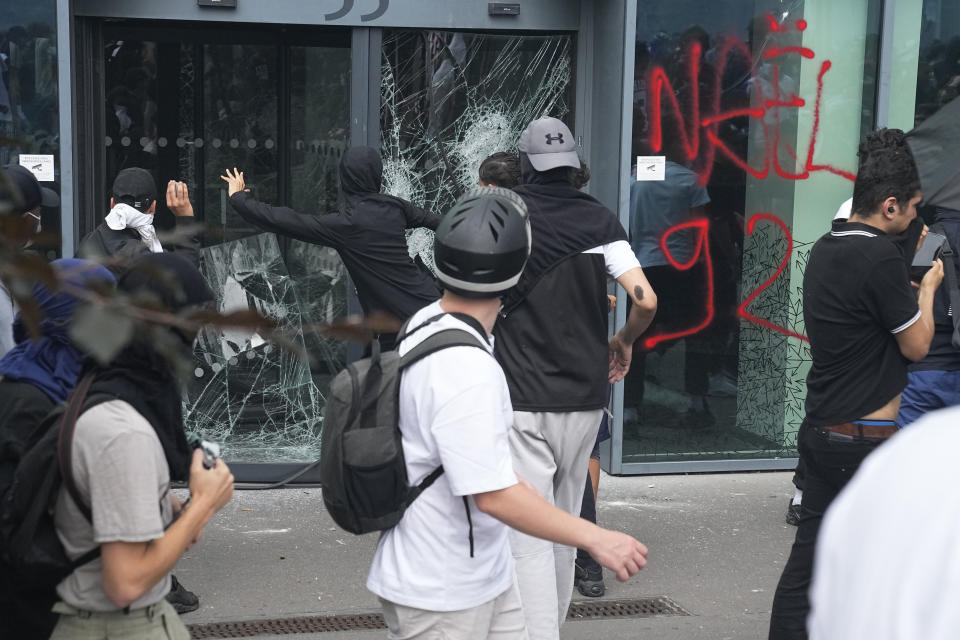 FILE - Youths smash a shop window after a march for Nahel, Thursday, June 29, 2023 in Nanterre, outside Paris. In all, more than 3,600 people have been detained in the unrest across France since the death of Nahel on June 27, with an average age of 17, according to the Interior Ministry. The violence left more than 800 law enforcement officers injured, French courts are working overtime to process the arrests, including opening their doors through the weekend, with fast-track hearings around an hour long and same-day sentencing. (AP Photo/Michel Euler, File)