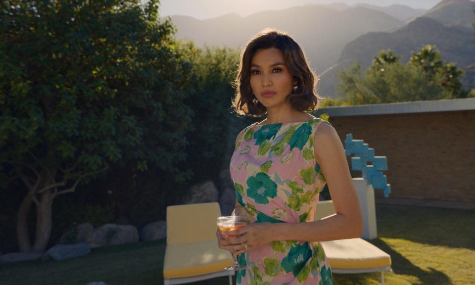 Gemma Chan in a floral dress holding a drink