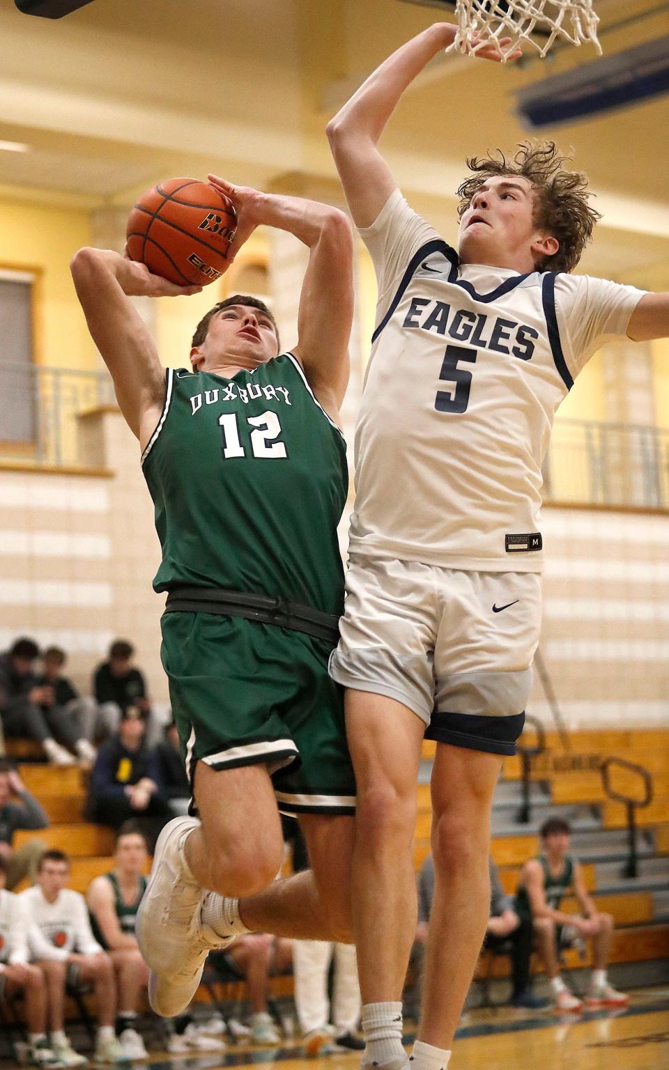 Zachary Falls of Duxbury lays up a shot under pressure from Eagle Nick Marcel.Plymouth North hosted Duxbury in boys basketball action on Friday February 3, 2023 