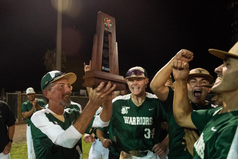 Jupiter head coach Andy Mook raises the district championship trophy as the team cheers after the end of the District 11-7A championship baseball game between host Jupiter and Palm Beach Central on Thursday, May 4, 2023, in Jupiter, Fla. Final score, Jupiter, 11, Palm Beach Central, 3.