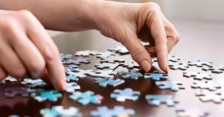 closeup of hands putting together a jigsaw puzzle