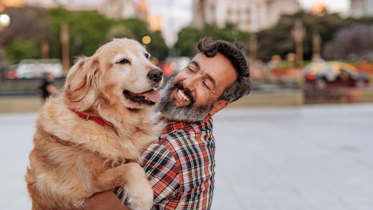  Man hugging his golden retriever on the streets of Buenos Aires. 