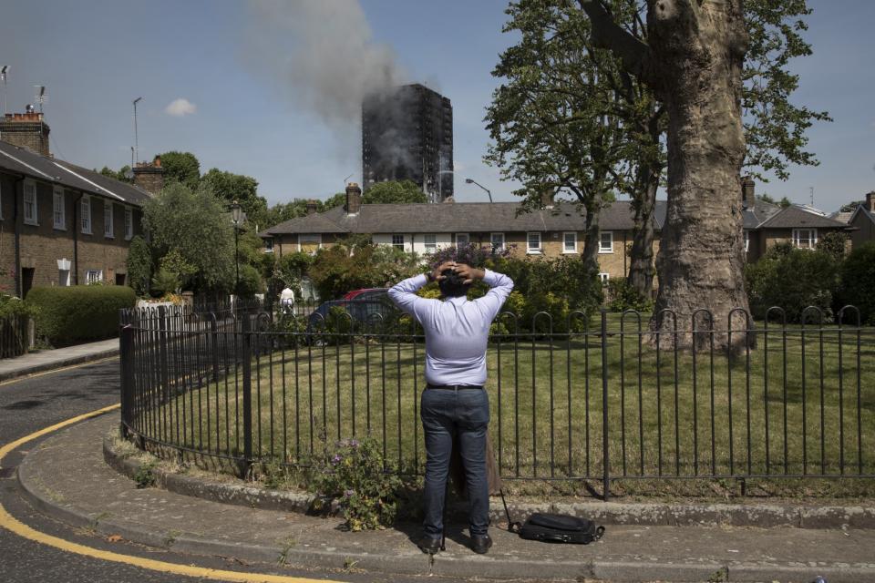 <p>A person looks up at smoke rising as emergency fire services tackle the blaze at Grenfell Tower near Notting Hill on June 14, 2017 in West London, England (Photo: Mike Kemp/In Pictures via Getty Images) </p>