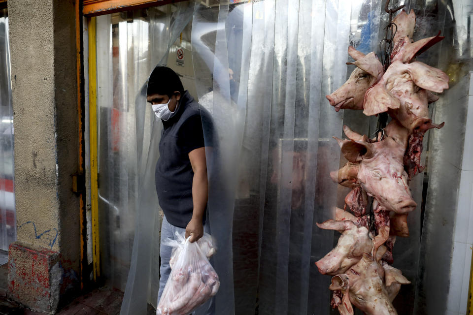 A costumer leaves a butchery at the Mataderos meat market in Buenos Aires, Argentina, Monday, April 20, 2020. According to butchers, sales have dropped at least 50% since the lockdown to help contain the spread of the new coronavirus. (AP Photo/Natacha Pisarenko)