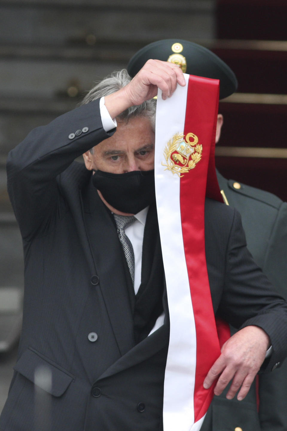 Peru's outgoing President Francisco Sagasti removes his presidential sash outside Congress before the inauguration of President-elect Pedro Castillo in Lima, Peru, Wednesday, July 28, 2021. (AP Photo/Francisco Rodriguez)