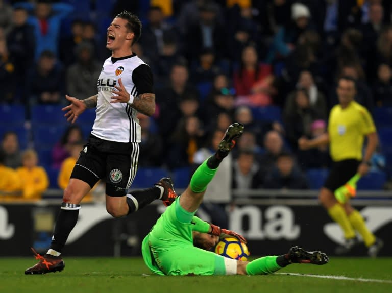 Espanyol's goalkeeper Pau Lopez gets the ball next to Valencia's Santiago Mina Lorenzo (L) during their Spanish La liga match, at the RCDE Stadium in Cornella de Llobregat, on November 19, 2017