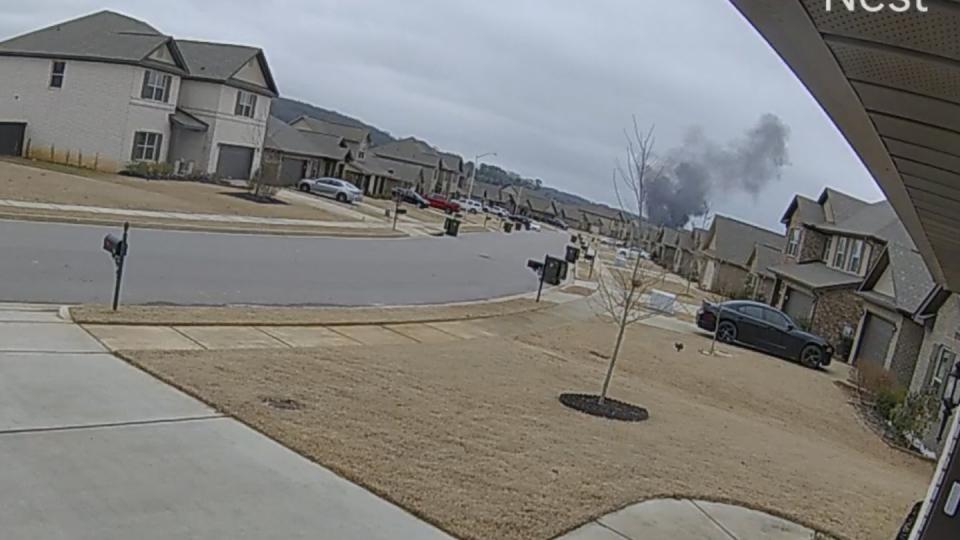 In this image made from video taken from a Nest camera provided by Mia McShan, a cloud of black smoke rises from where a Black Hawk helicopter crashed on Wednesday, Feb. 15, 2023, in Alabama. U.S. military officials say two people on board were killed.  (Mia McShan via AP)