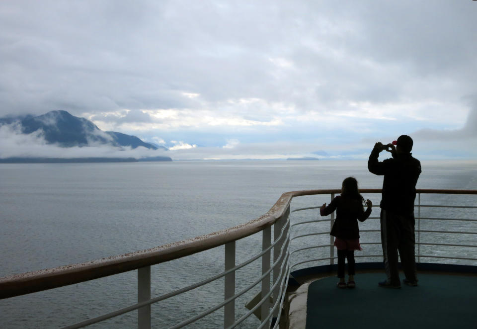 FILE - In this July 28, 2014, file photo, a cruise ship passenger takes photos of Alaska's Inside Passage. The Canadian government has extended a ban on cruise ships through February 2022, which is expected to block trips from visiting Alaska this year. Transport Canada announced the extension of the ban put in place because of the COVID-19 pandemic. (AP Photo/Kathy Matheson, File)