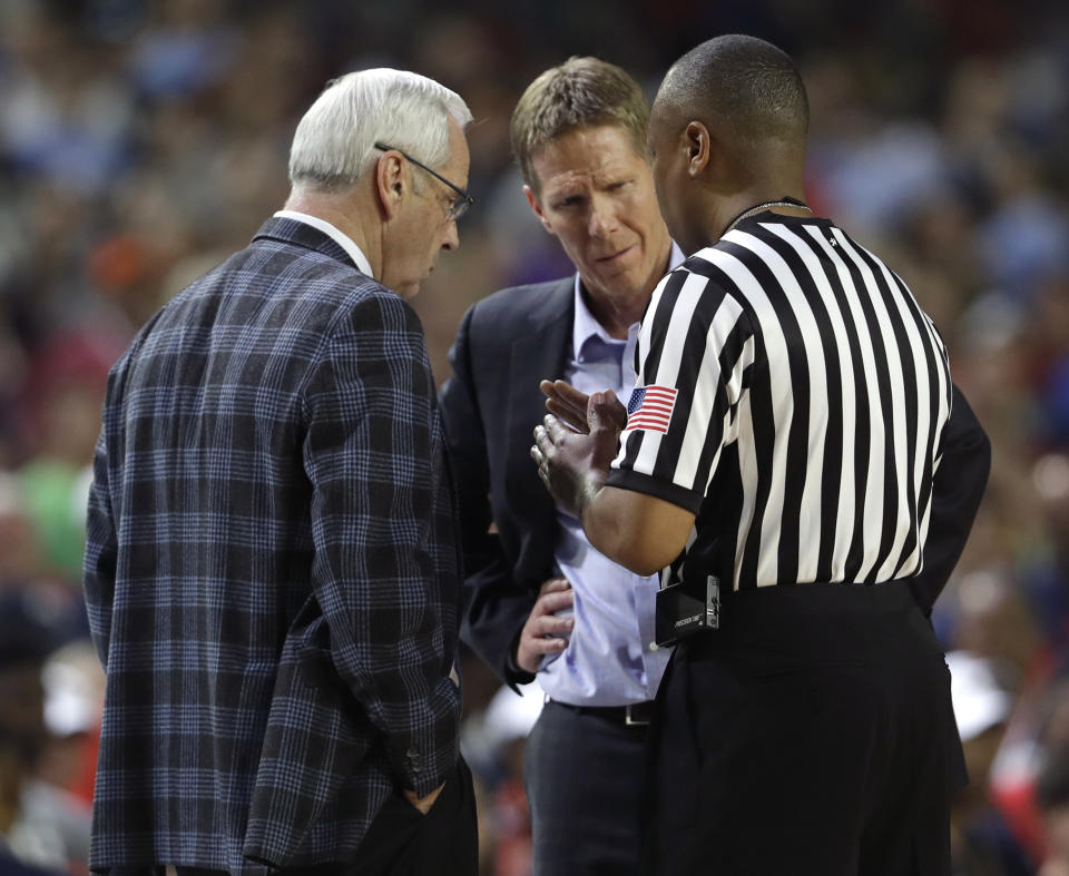 An official explains a call to North Carolina head coach Roy Williams, left, and Gonzaga head coach Mark Few, center, during the second half in the finals of the Final Four NCAA college basketball tournament, Monday, April 3, 2017, in Glendale, Ariz. Gonzaga center Przemek Karnowski was called for a flagrant foul on the play. (AP Photo/David J. Phillip)