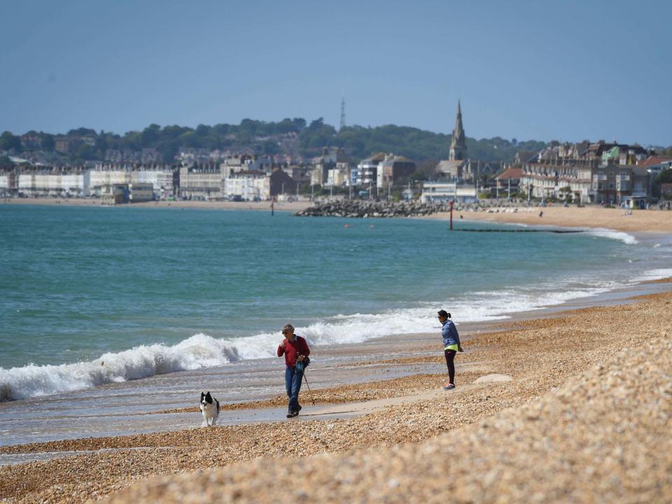 A man walks his dog on Preston beach in Weymouth on Sunday: Getty