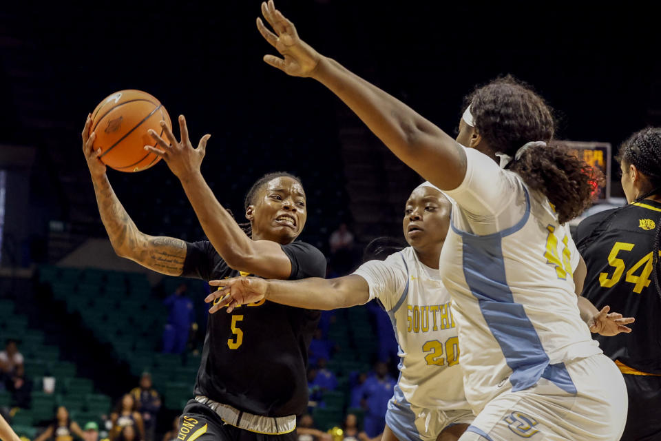 Arkansas-Pine Bluff guard Jelissa Reese (5) drives to the basket as Southern guard Amani Mcwain (20) and forward Raven White (44) defends during the second half of an NCAA college basketball game in the championship of the Southwestern Athletic Conference Tournament, Saturday, March 11, 2023, in Birmingham, Ala. (AP Photo/Butch Dill)
