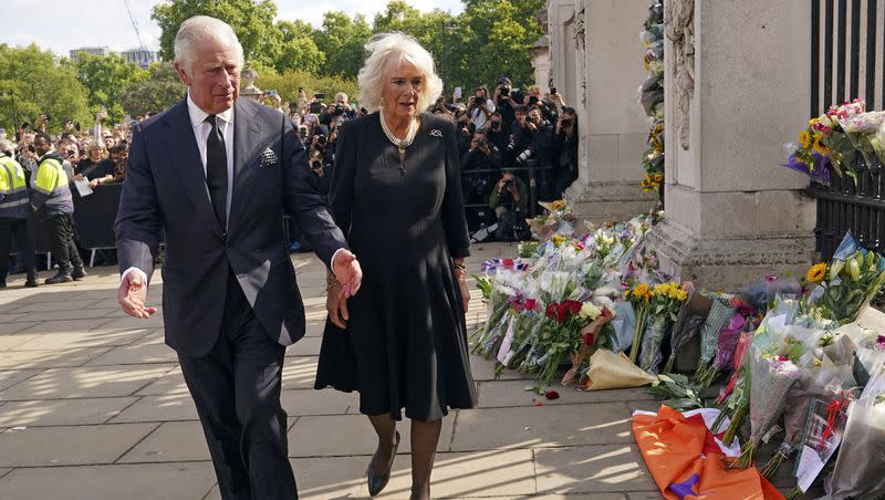 King Charles III and Queen Camilla look at floral tributes at Buckingham Palace following the death of Queen Elizabeth II.
