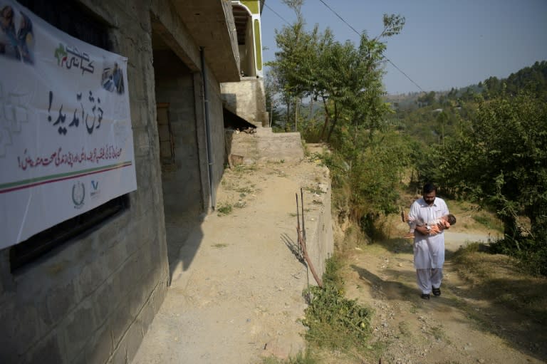 A Pakistani resident carries his sick son as they arrive at an online treatment clinic in the remote Bhosa village of Mansehra district