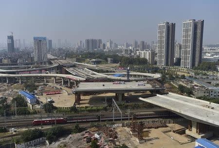 An overpass is seen under construction as a train travels past in Wuhan, Hubei province, October 24, 2014. REUTERS/Stringer