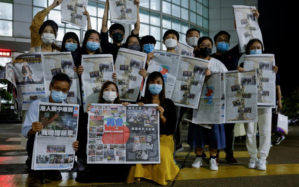 Staff outside Apple Daily's office with the final edition of the paper - REUTERS