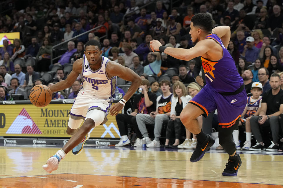 Sacramento Kings guard De'Aaron Fox (5) drives on Phoenix Suns guard Devin Booker during the first half of an NBA basketball game, Saturday, March 11, 2023, in Phoenix. (AP Photo/Rick Scuteri)