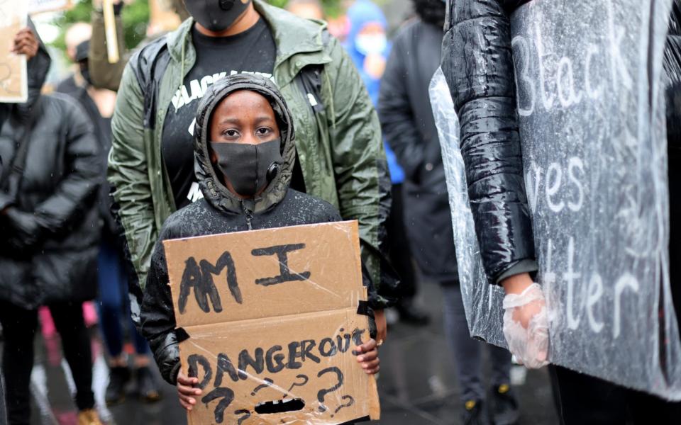 A child wearing a protective face mask holds a placard during a BLM protest in Leicester - Carl Recine/REUTERS