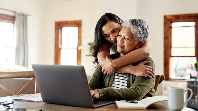 Cropped shot of an attractive young woman hugging her grandmother before helping her with her finances on a laptop.