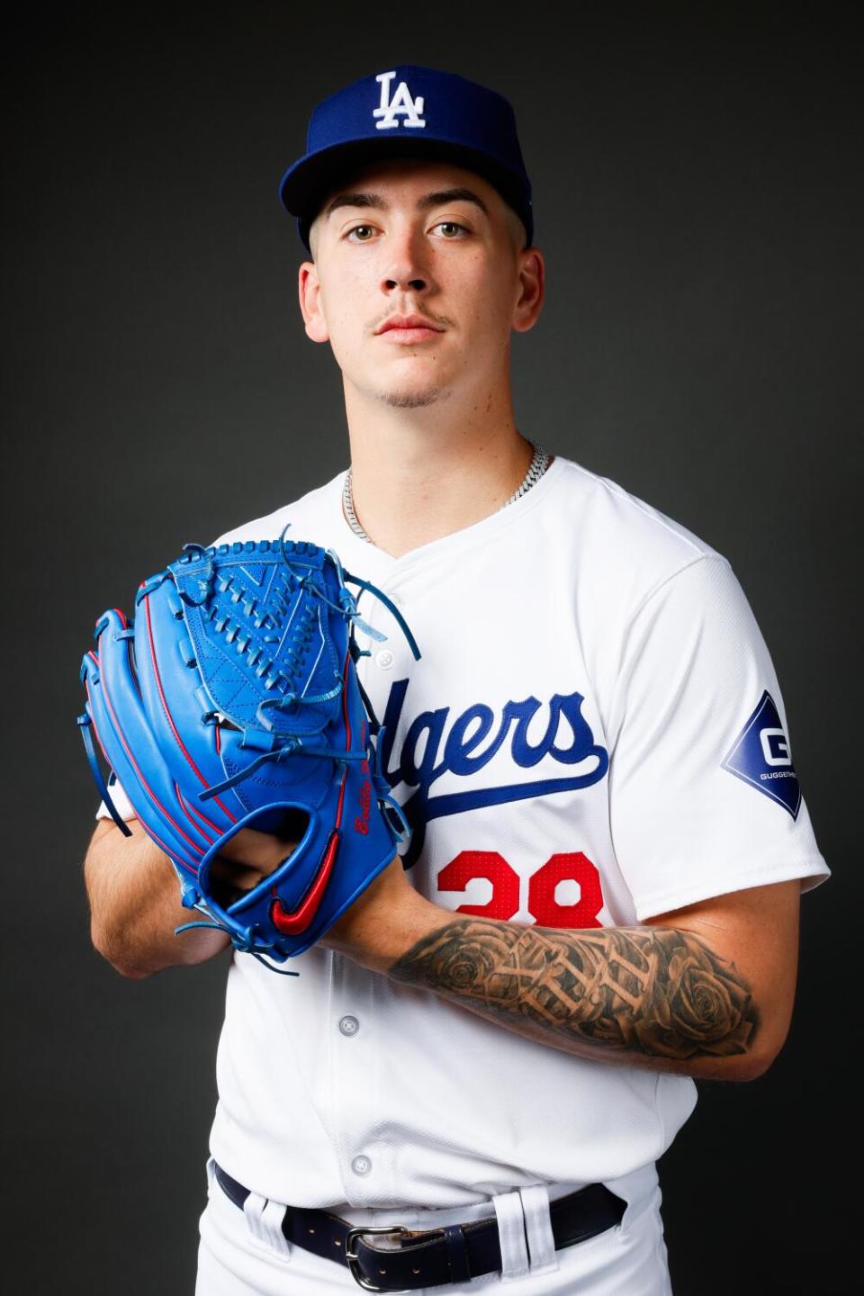 The Dodgers' Bobby Miller posing in uniform holding a blue glove for a picture.